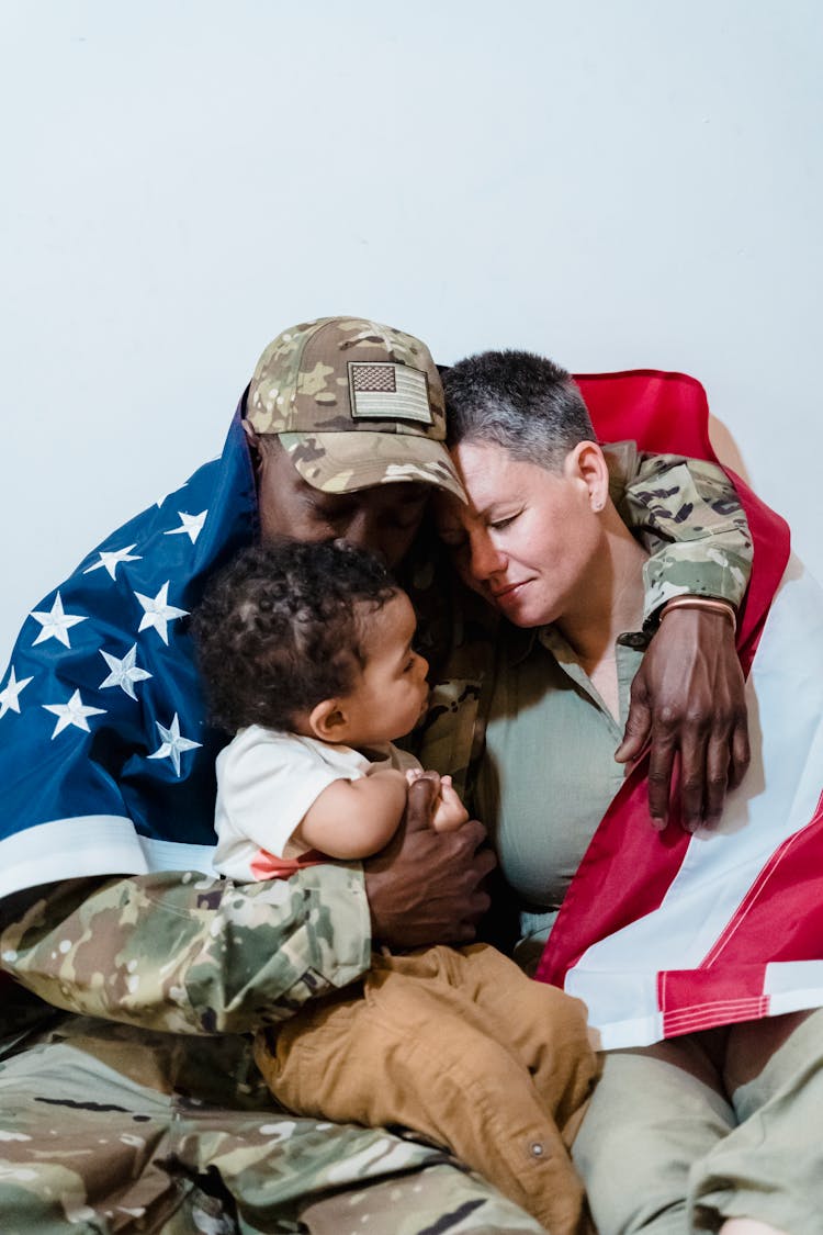 Army Couple Wrapped With An American Flag Sitting Beside Their Son 