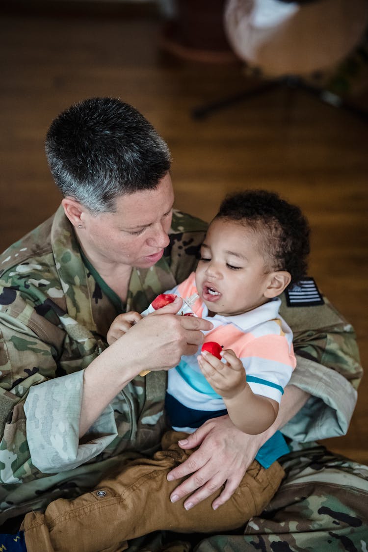 Woman In Military Uniform Carrying A Child