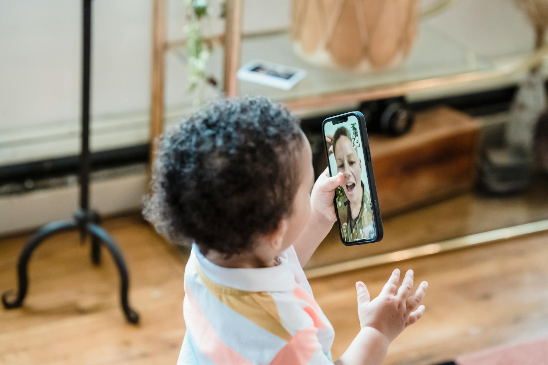 A young child interacts with a video call on a smartphone indoors.