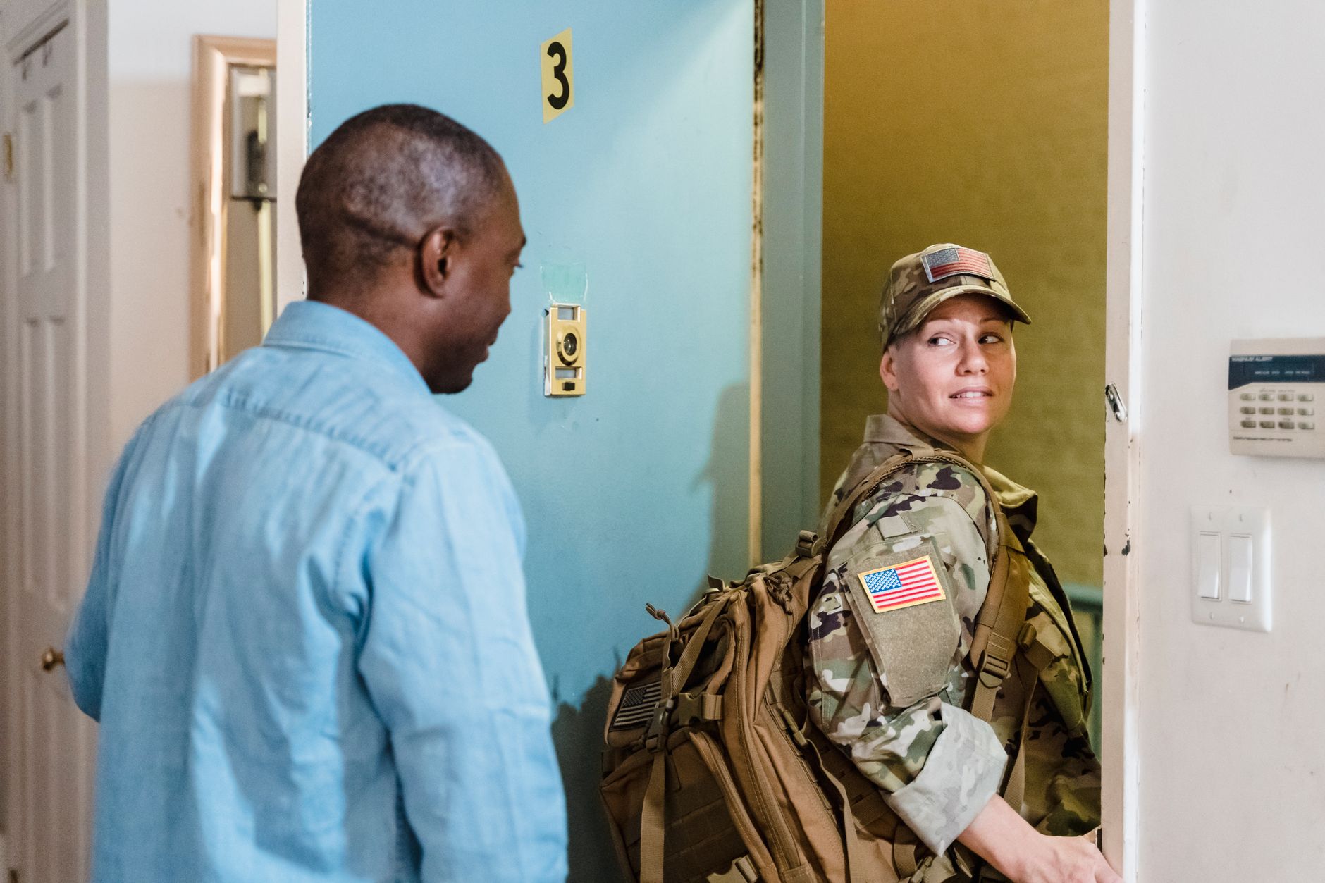 A soldier in uniform reunites with her partner at home, showcasing love and diversity.