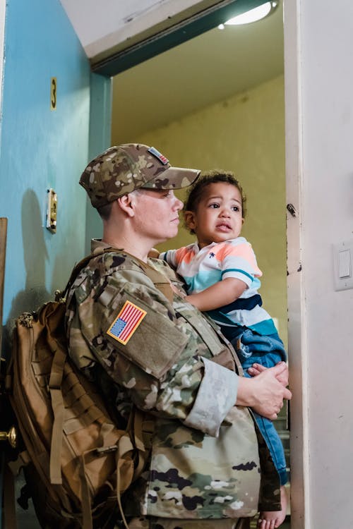 Free Person in Military Uniform Carrying a Child Stock Photo