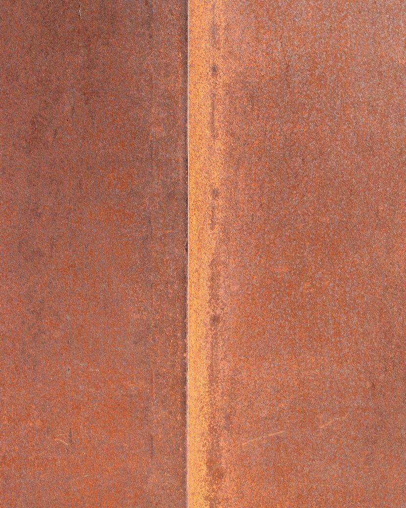 Two flat plates of weathering steel meeting at a vertical joint, both faces covered in an even orange-brown oxide layer.