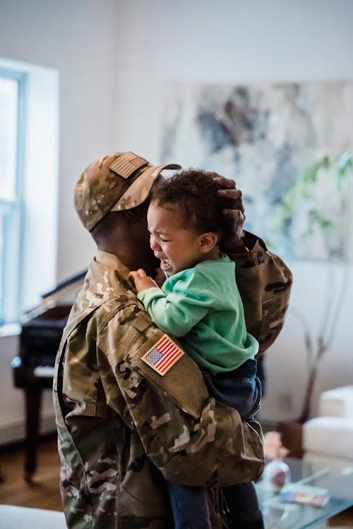 A Person in Military  Uniform Carrying a Crying Child