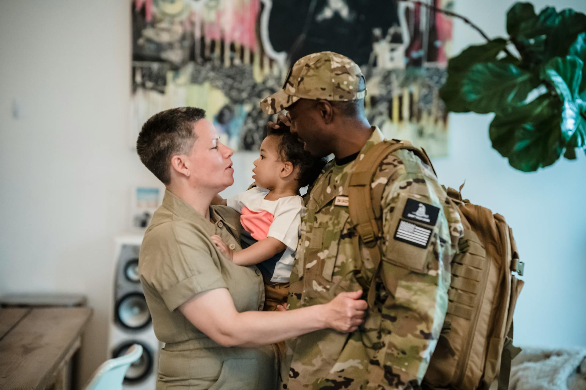 A Woman Carrying a Child beside a Man in Military Uniform