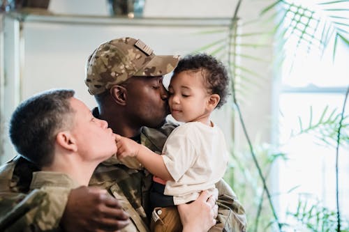 A Man in Military Uniform Kissing his Child