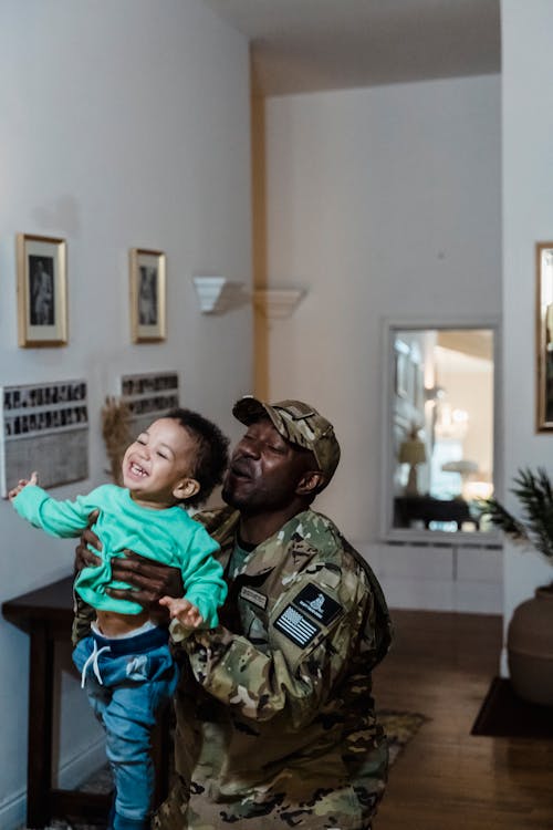 A Father in Uniform Playing with His Kid