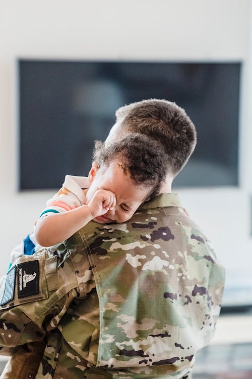 Free A Person in Military Uniform Carrying a Child Crying Stock Photo