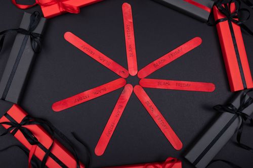 Free Festive Black Friday setup with gift boxes and decorated popsicle sticks on a black background. Stock Photo