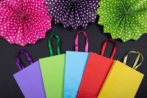 Free Vibrant flat lay of colorful shopping bags and polka dot decorations on a black background. Stock Photo