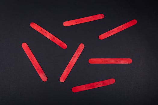 Red popsicle sticks with 'Black Friday' text on a black backdrop, ideal for sales and promotions.