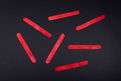 Free Red popsicle sticks with 'Black Friday' text on a black backdrop, ideal for sales and promotions. Stock Photo