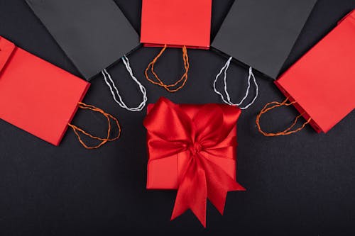 Free A Box Wrapped in Red Ribbon Beside the Paper Bags Stock Photo