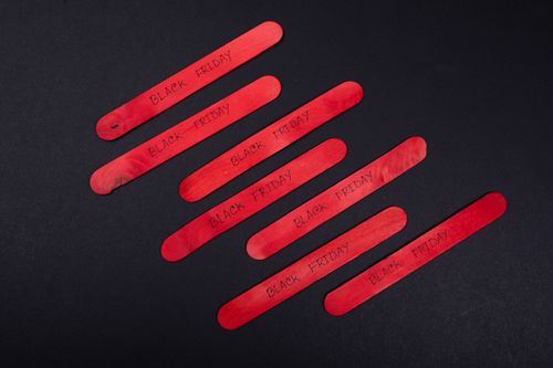 Free Red wooden sticks with Black Friday text on a black background, perfect for promotional visuals. Stock Photo