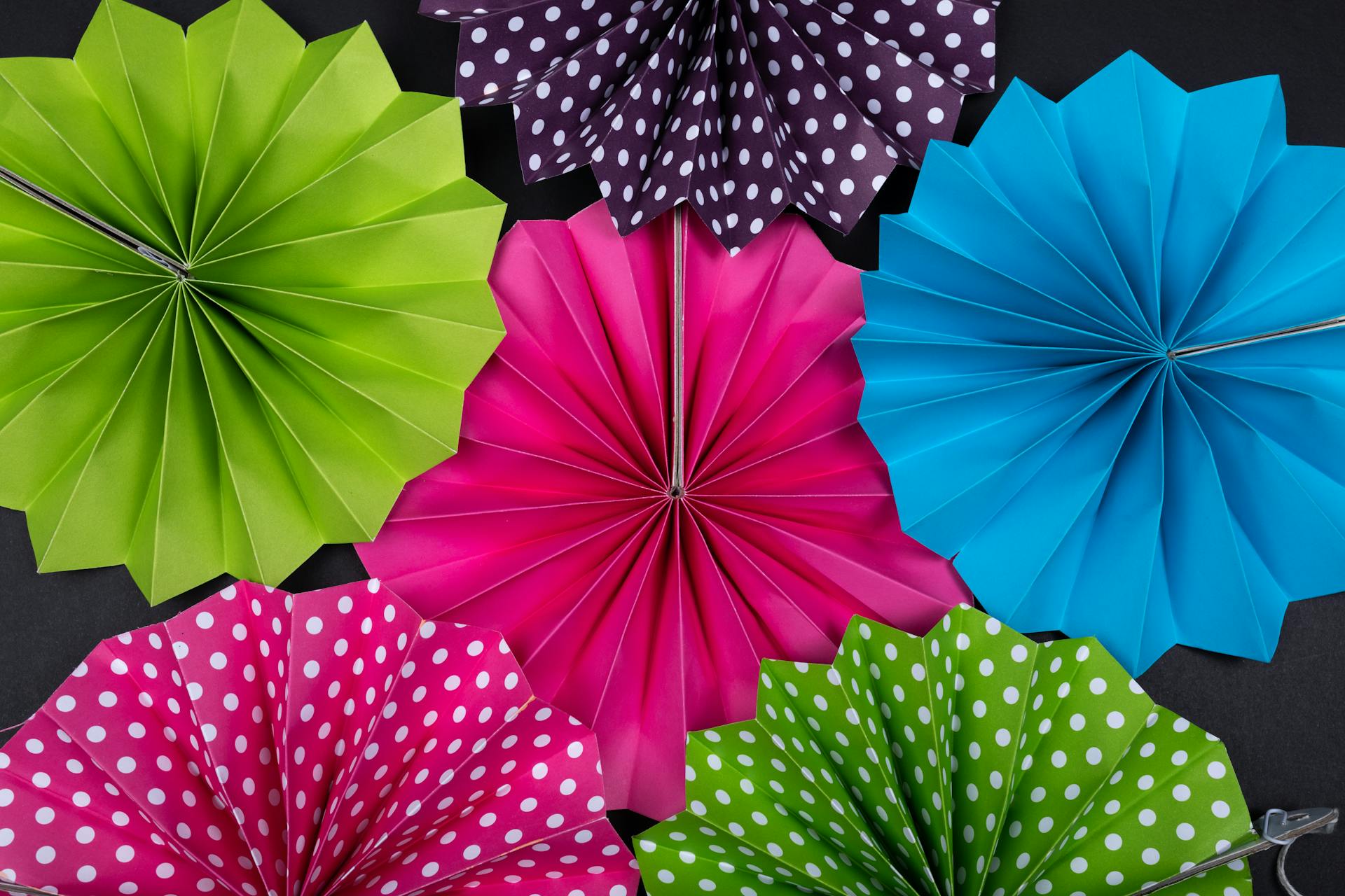 A vibrant assortment of folded origami paper fans in various colors and patterns.