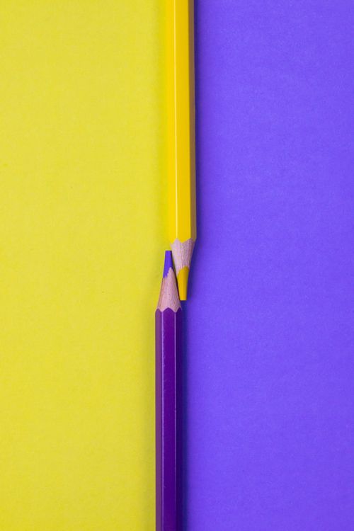 Free Close-up of yellow and purple pencils on matching color backgrounds, showcasing contrasting hues. Stock Photo