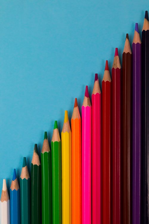 Free Colorful pencils arranged vertically on a turquoise background, great for art and education themes. Stock Photo