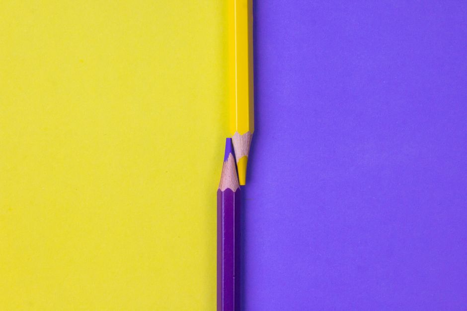 Bright yellow and purple colored pencils aligned creatively with a minimalistic design.