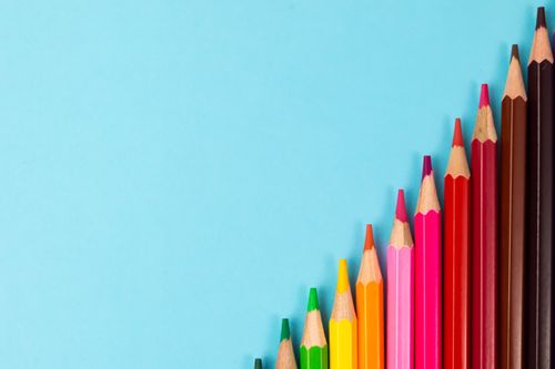 Free Bright colored pencils arranged in a row on a turquoise background, perfect for creativity concept. Stock Photo