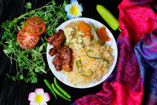 Delicious Asian fusion meal featuring fried rice with veggies and glazed chicken wings, styled against colorful background.