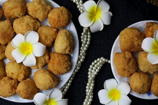 An artistic display of golden fried bites adorned with white flowers and pearl strands.