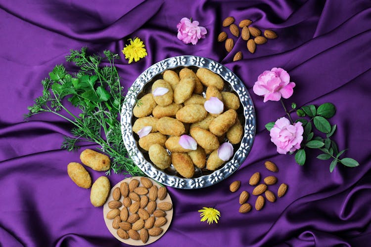 Overhead Shot Of A Plate Of Croquettes With Flower Petals Beside Almonds