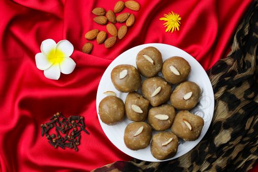 Gourmet halva dessert balls with almonds on vibrant red satin fabric.