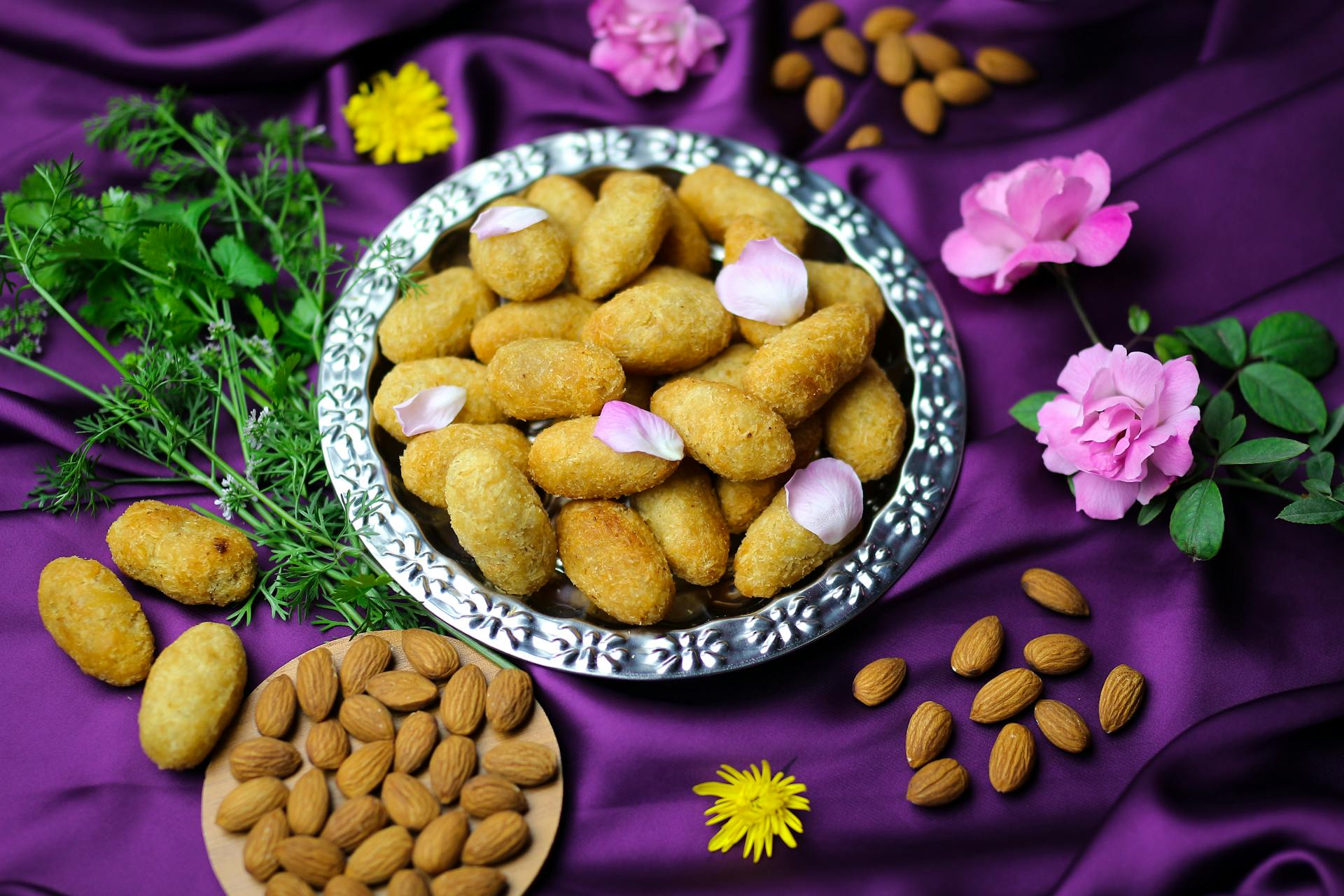 Crispy croquettes on a decorative platter surrounded by almonds and flowers.