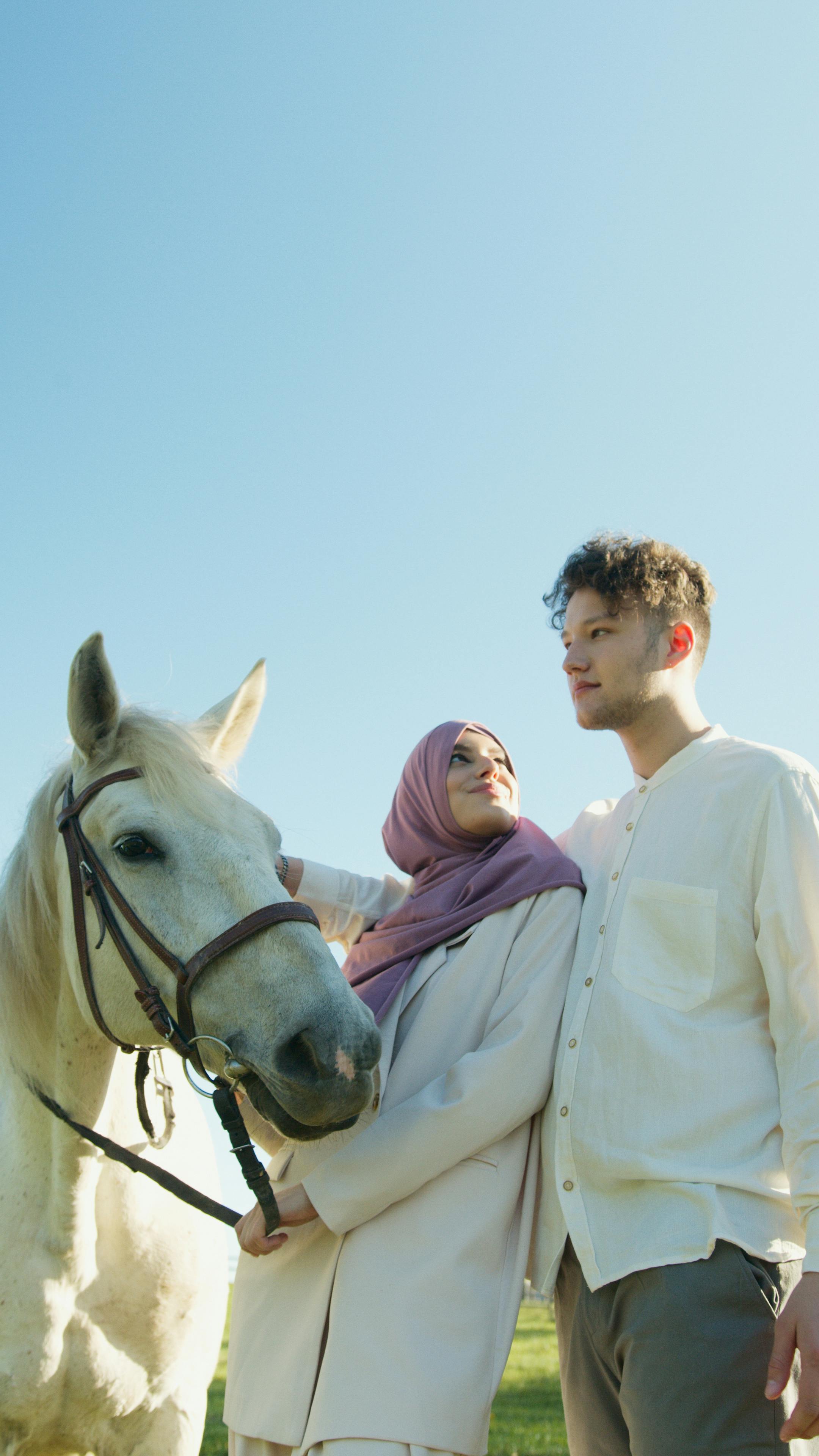 a couple standing beside the white horse