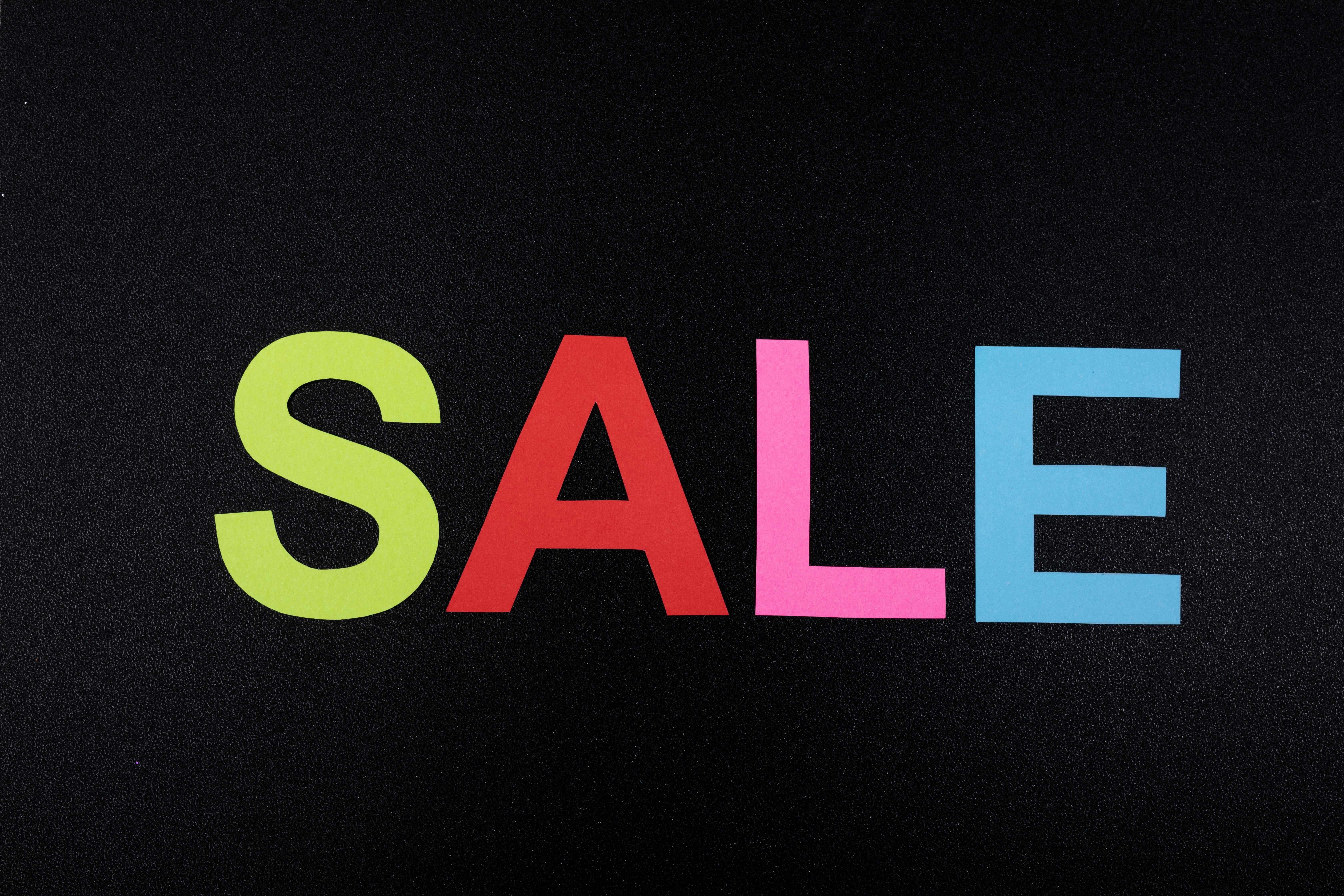 Multicolor letters spelling SALE on a textured black surface, perfect for promotional use.