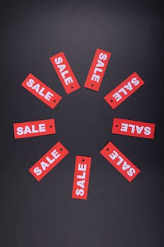 Circular arrangement of red sale tags on a black background, perfect for promotions.