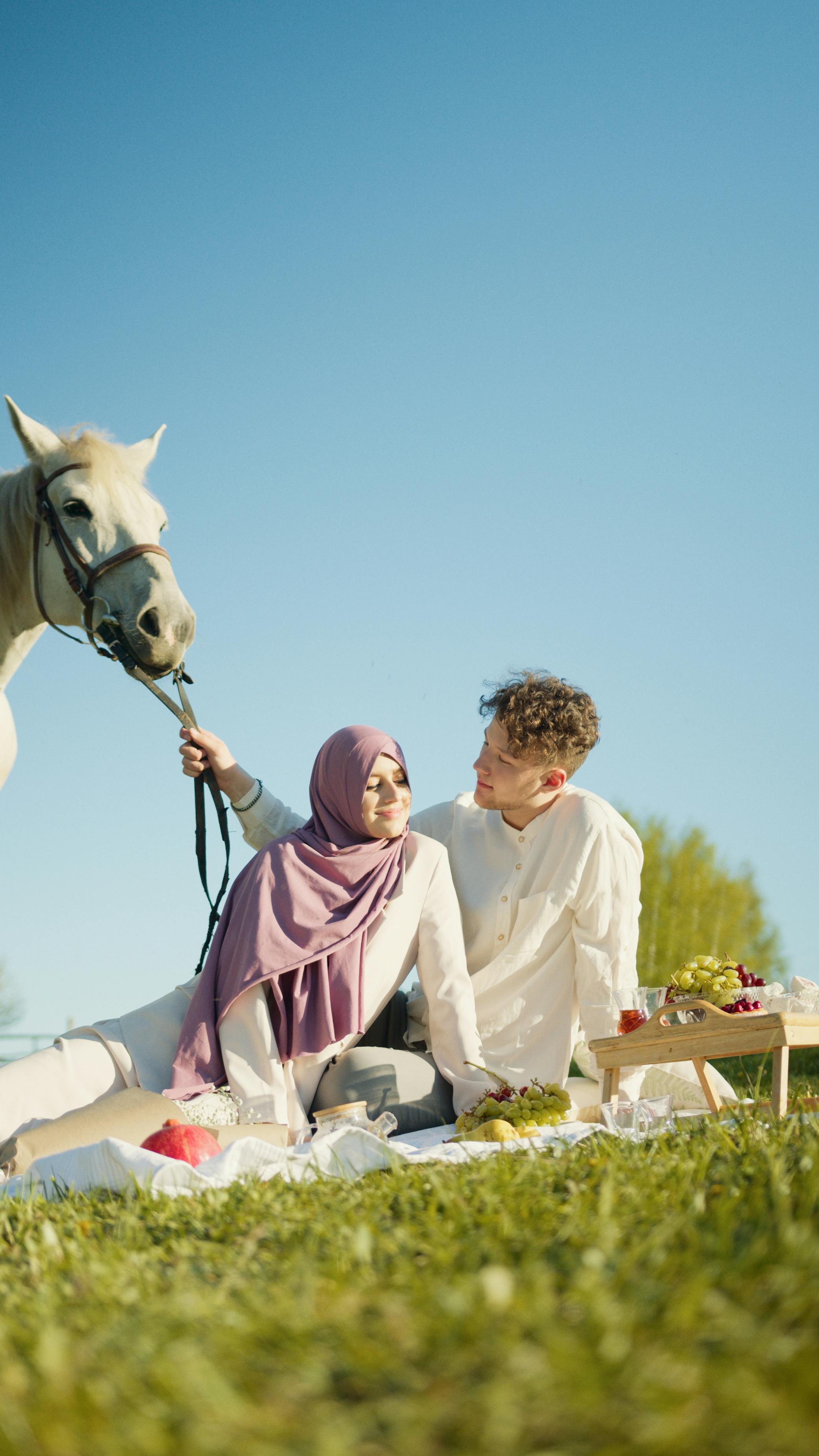 a couple sitting on white picnic blanket