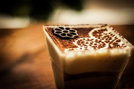 A close-up view of a creamy dessert coffee with artistic chocolate powder design.
