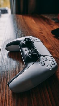 Modern gaming controller close-up on wooden surface, highlighting its design and texture.