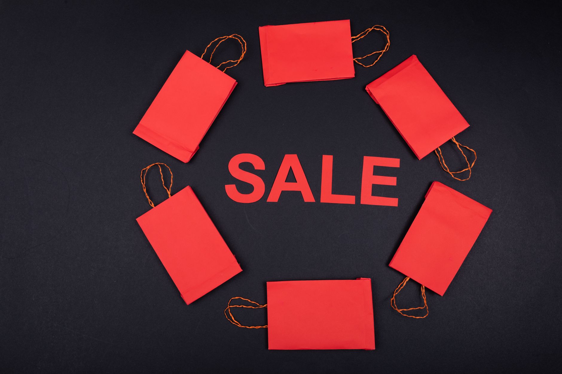 Circular arrangement of red paper bags with 'SALE' text on a dark background.