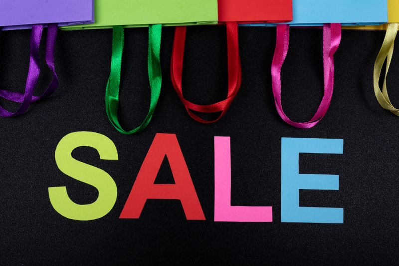 Vibrant shopping bags with SALE text on a black background, ideal for promotions.