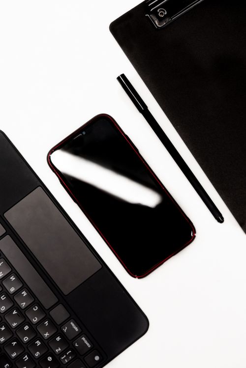 Free Flat lay of a smartphone, laptop, pen, and clipboard on a desk. Stock Photo