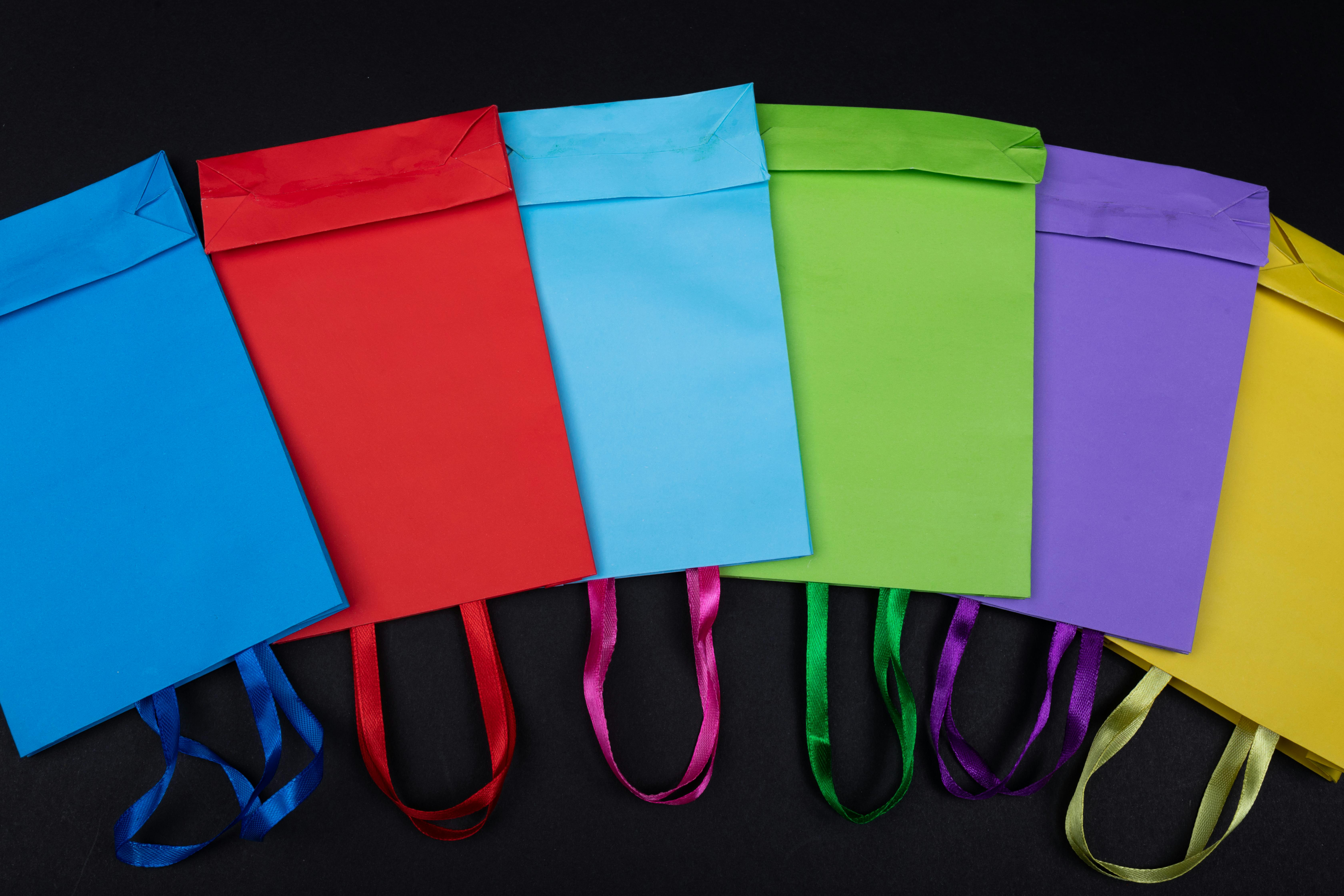 Vibrant flat lay of colorful shopping bags displayed on a black background, ideal for retail themes.