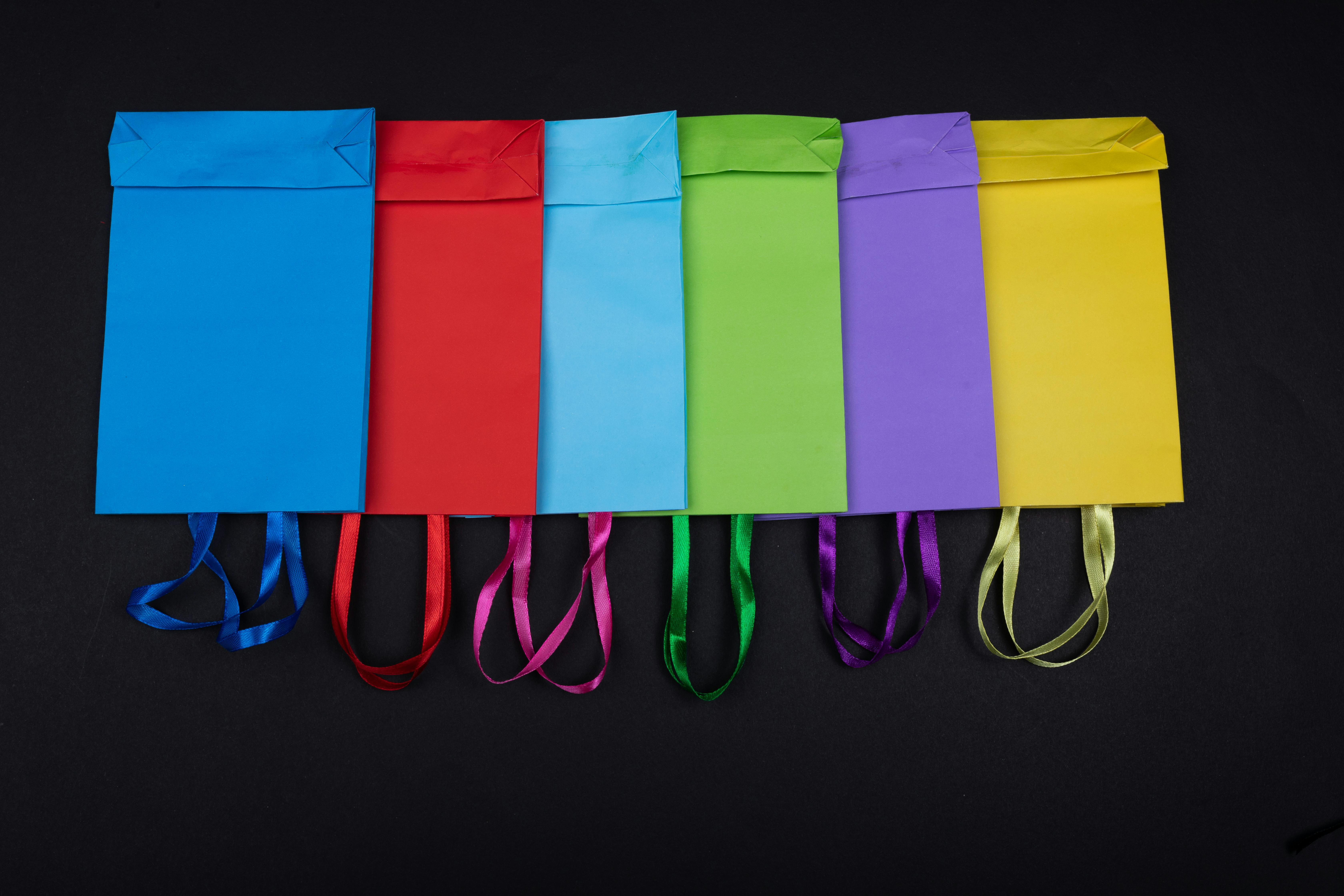 An array of vibrant shopping bags on a black background, showcasing variety and color.