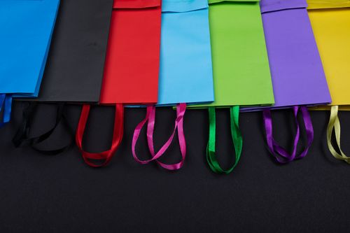Free Brightly colored paper shopping bags arranged on a black background, highlighting vivid colors. Stock Photo