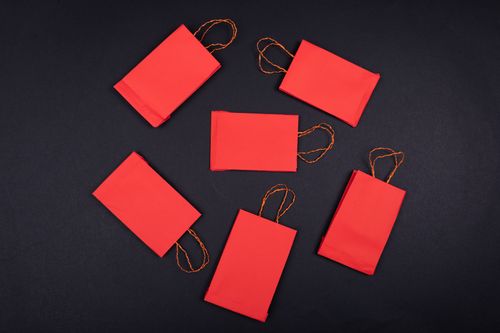 Free A vibrant flatlay of red paper bags arranged on a black background, creating a bold contrast. Stock Photo