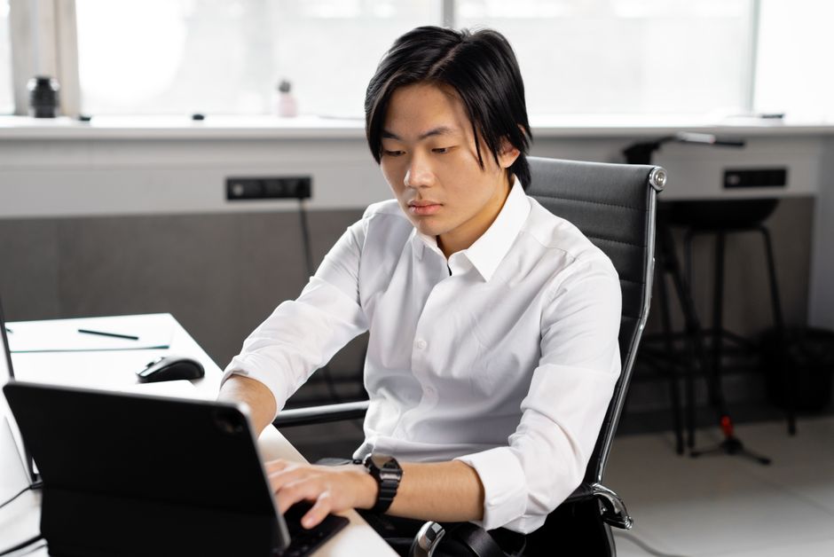 young adult sitting at a desk setting financial goals on a laptop - how to manage daily expenses young adult sitting at a desk setting financial goals on a laptop - how to manage daily expenses