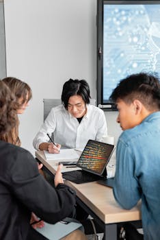 Group of professionals collaborating in an office setting with laptops and documents.