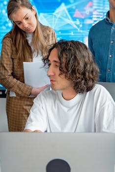A team of professionals discussing business strategy while analyzing data on a laptop.