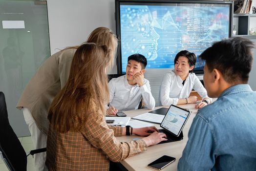 Team of professionals collaborating in an office with digital interface on background screen.