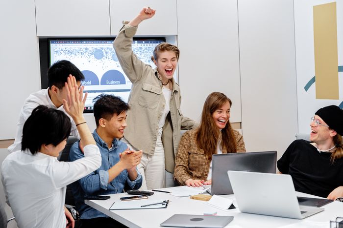 Team celebrating around laptops in a meeting room — photo by Mikhail Nilov on Pexels