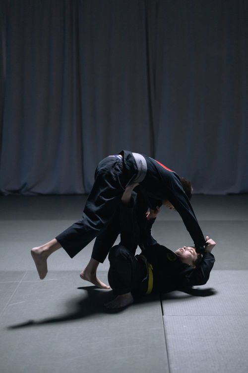 Free Two men engaged in intense Brazilian Jiu Jitsu sparring match indoors. Stock Photo