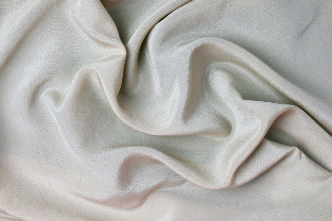 Soft folds of pale silver-cream satin fabric with a gentle sheen