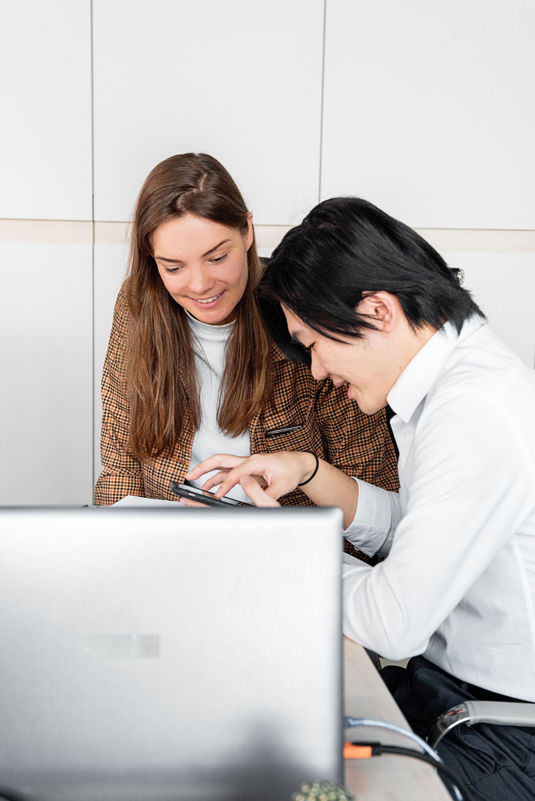 Business professionals using a smartphone and laptop in a modern office