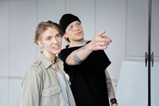 Two young adults discussing ideas in a modern office environment, focused and engaged.