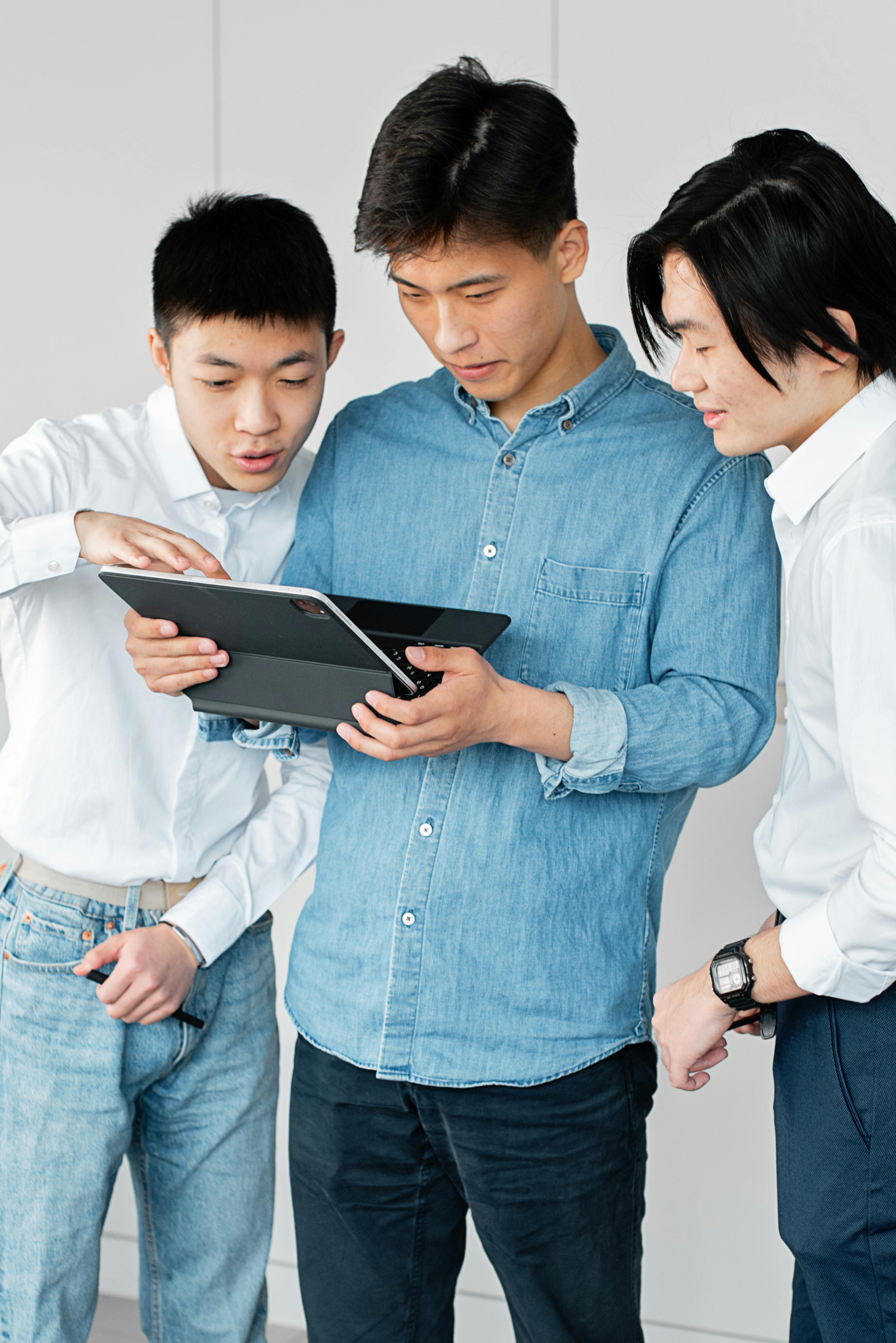 man in denim shirt holding laptop together with his friends